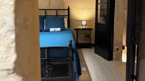 Un dormitorio con cama, mesita de noche, lámpara y una puerta.