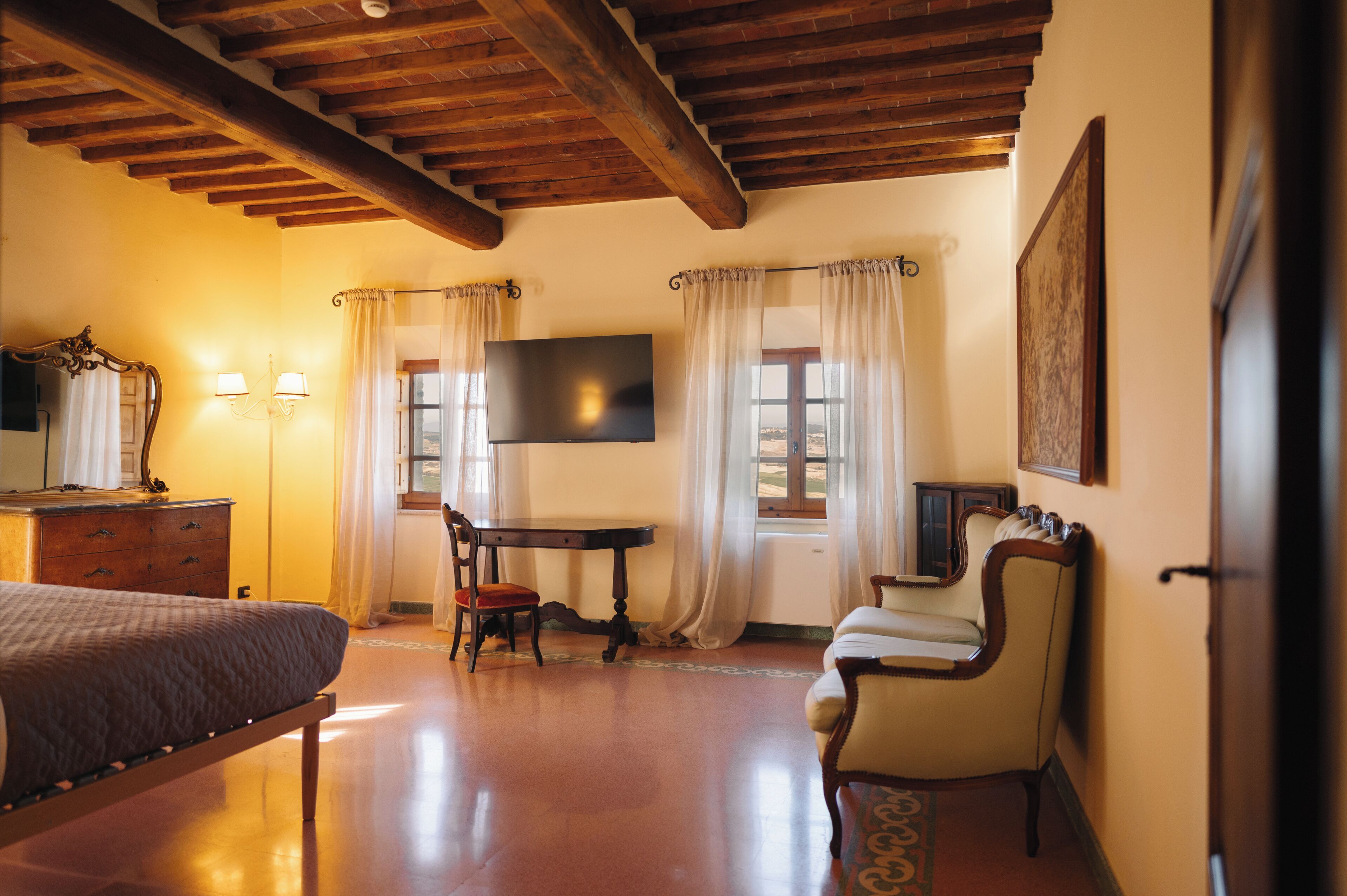 Una habitación con cama, escritorio, silla, televisor y cómoda.