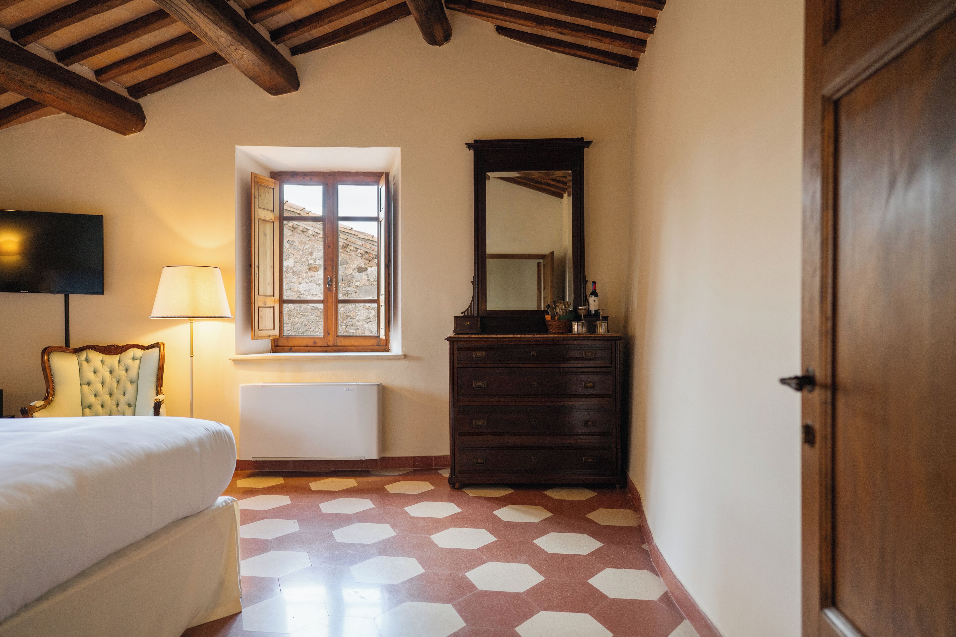 Un dormitorio con cama, cómoda, espejo, lámpara y ventana.