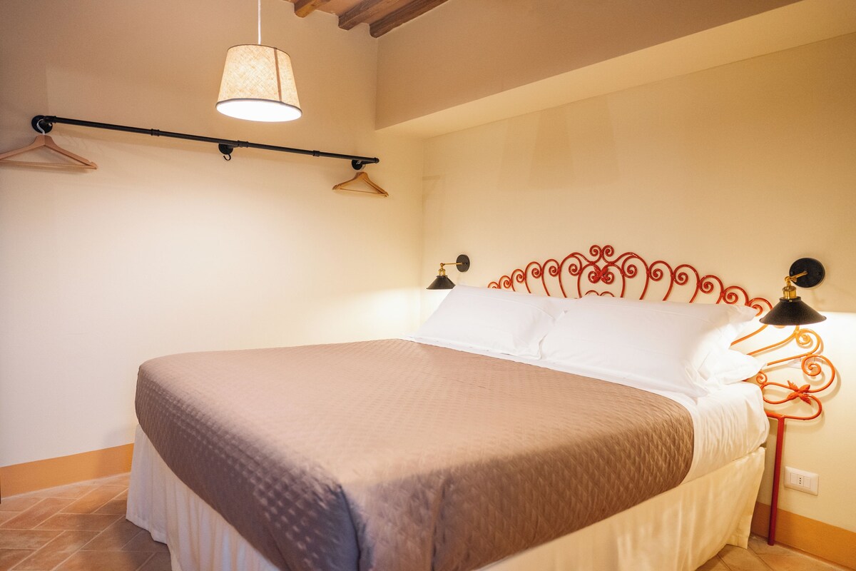 Une chambre à coucher avec un lit, un luminaire suspendu et une lampe fixée au mur.