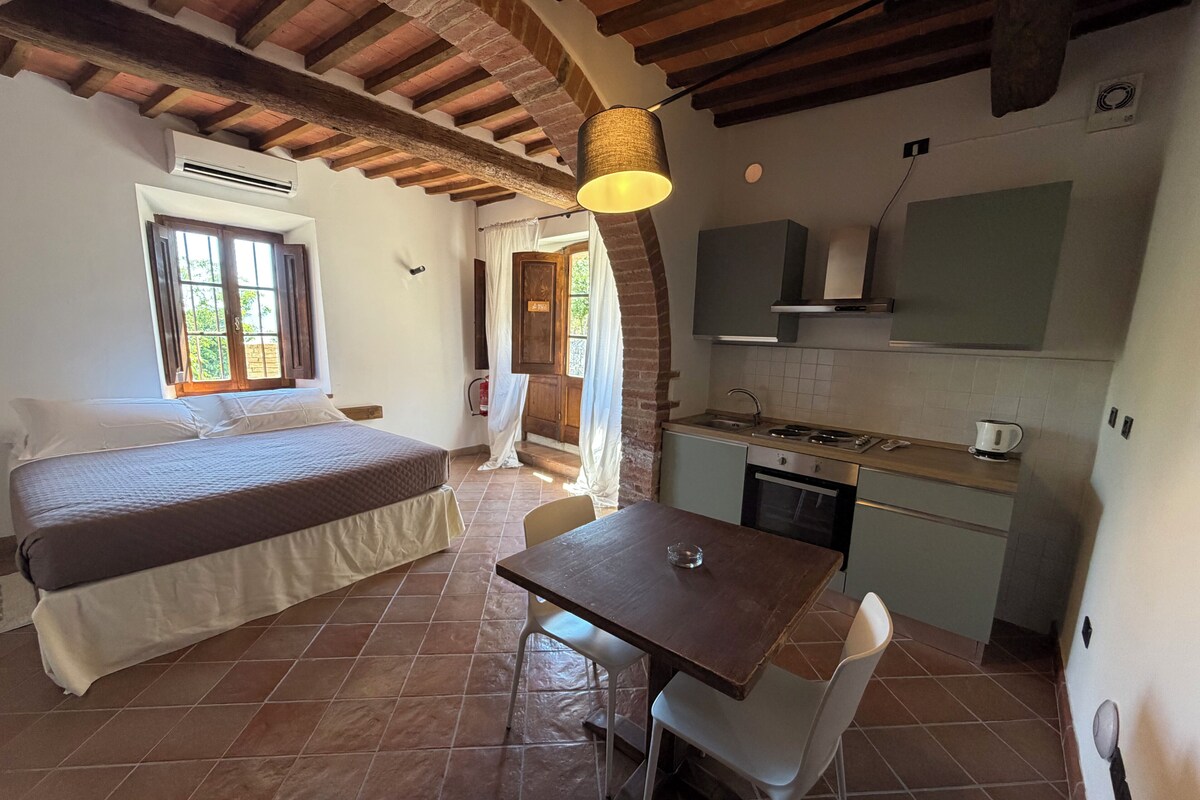 Une chambre avec un lit, une table à manger avec une chaise, une cuisine avec une cuisinière et une fenêtre.