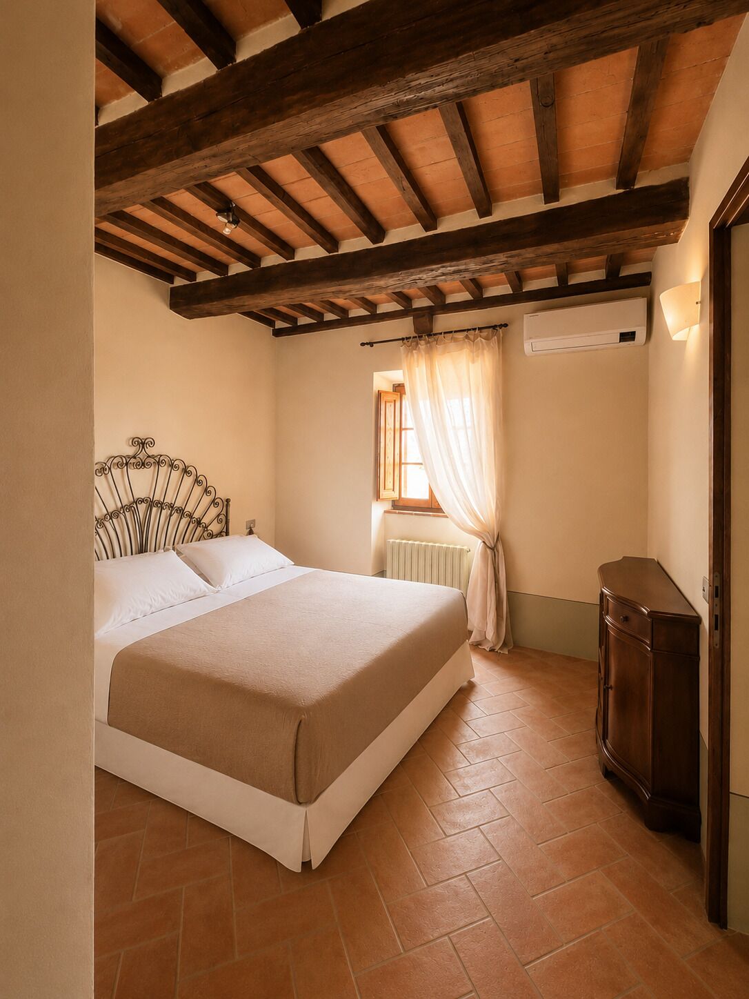 Un dormitorio con cama, un radiador, una ventana con cortinas y un armario de madera.