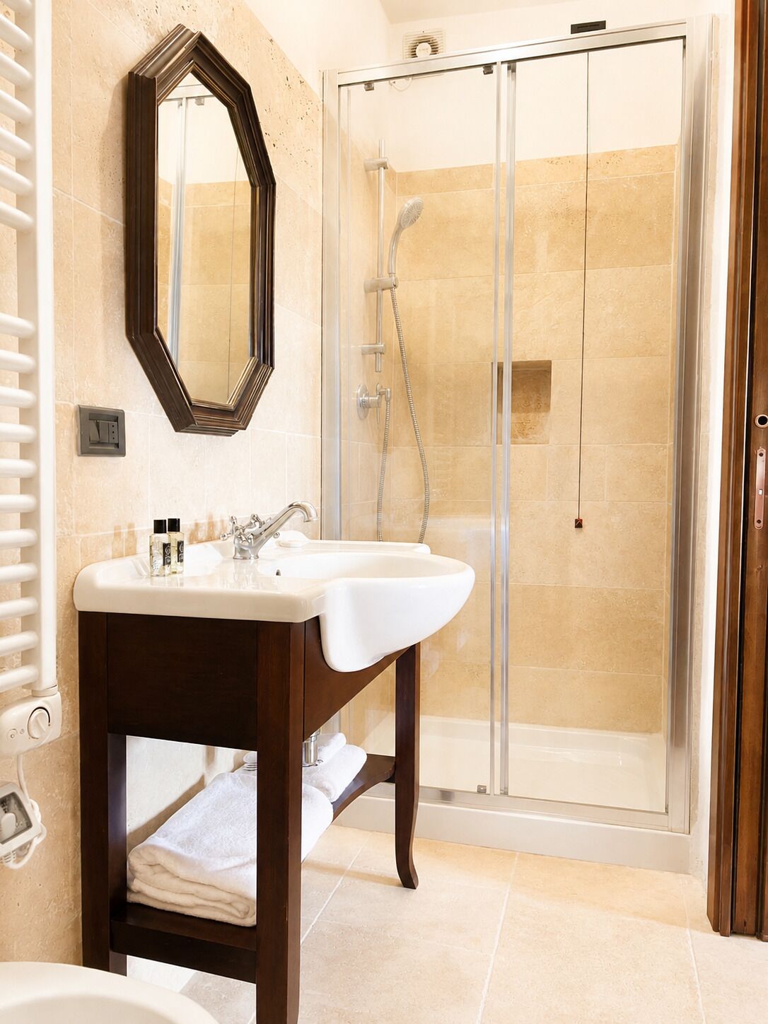 A bathroom with a shower, a sink, a mirror, and a towel rack.