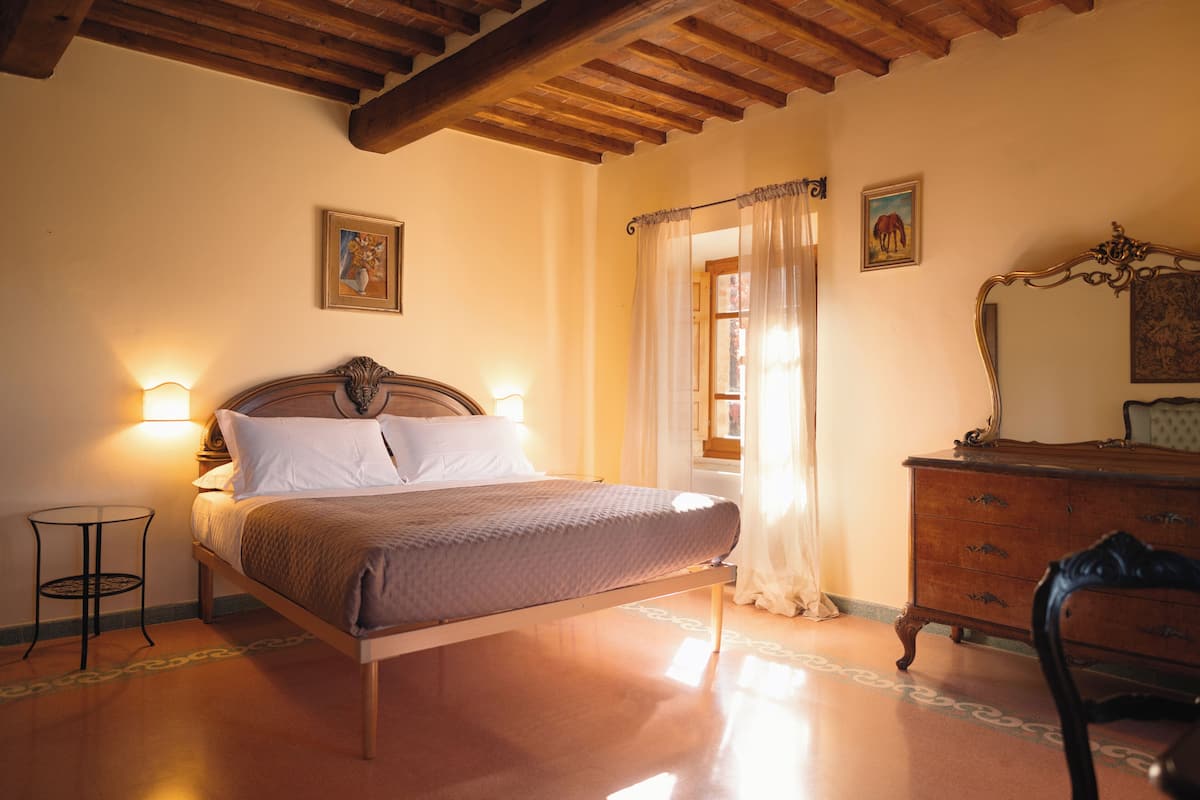 Een slaapkamer met een houten bed, een nachtkastje, een dressoir en een spiegel.