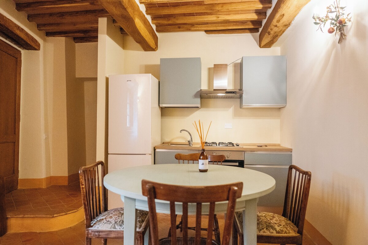 Cocina compacta con comedor, que incluye un refrigerador blanco, estufa y armarios.