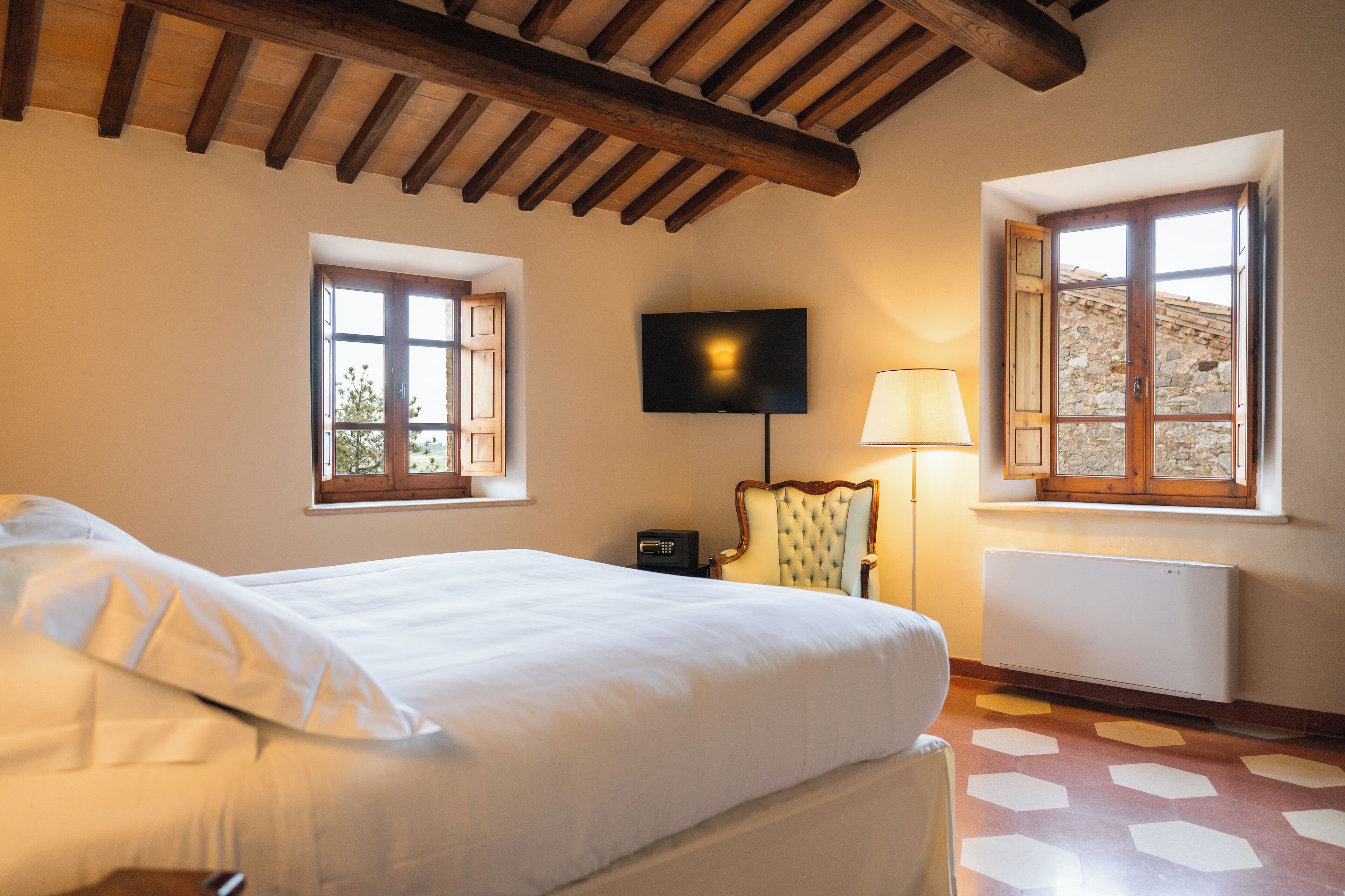A hotel room with a bed, a television, a chair, and a window with a view of the outside.