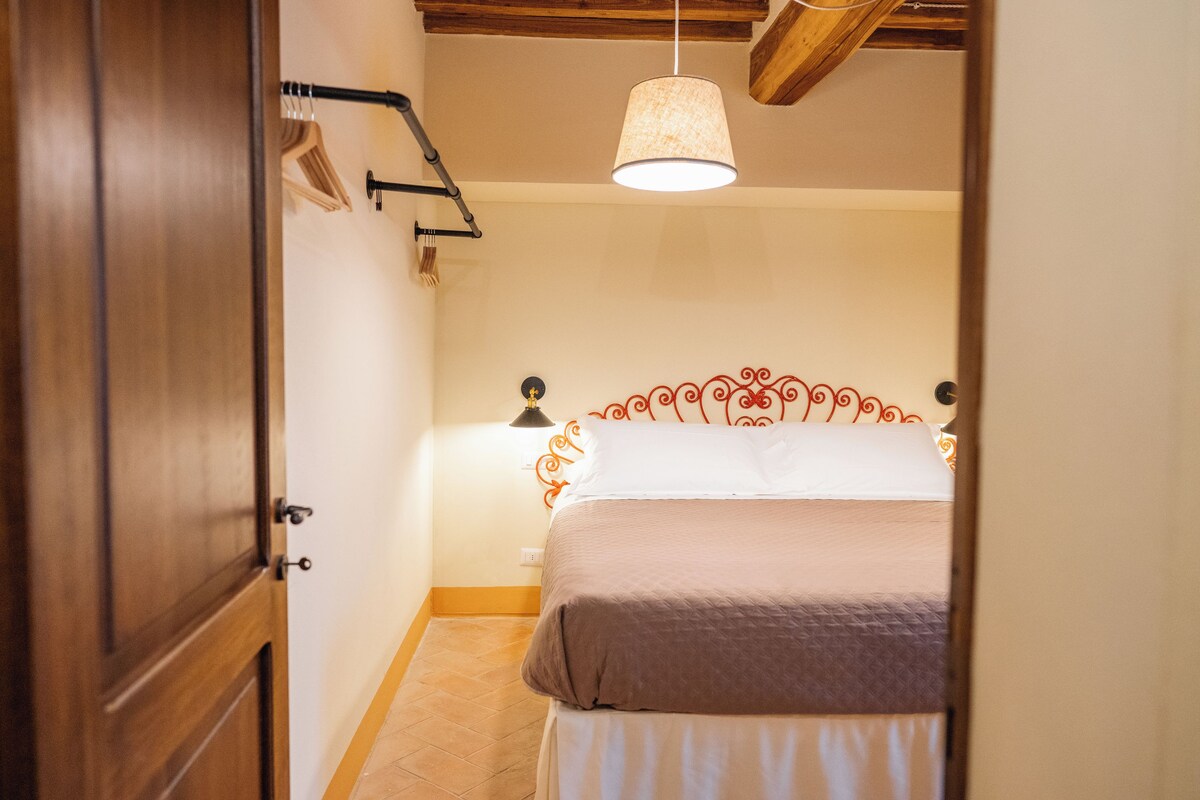 A bedroom with a bed, a hanging light fixture, and a wooden door.