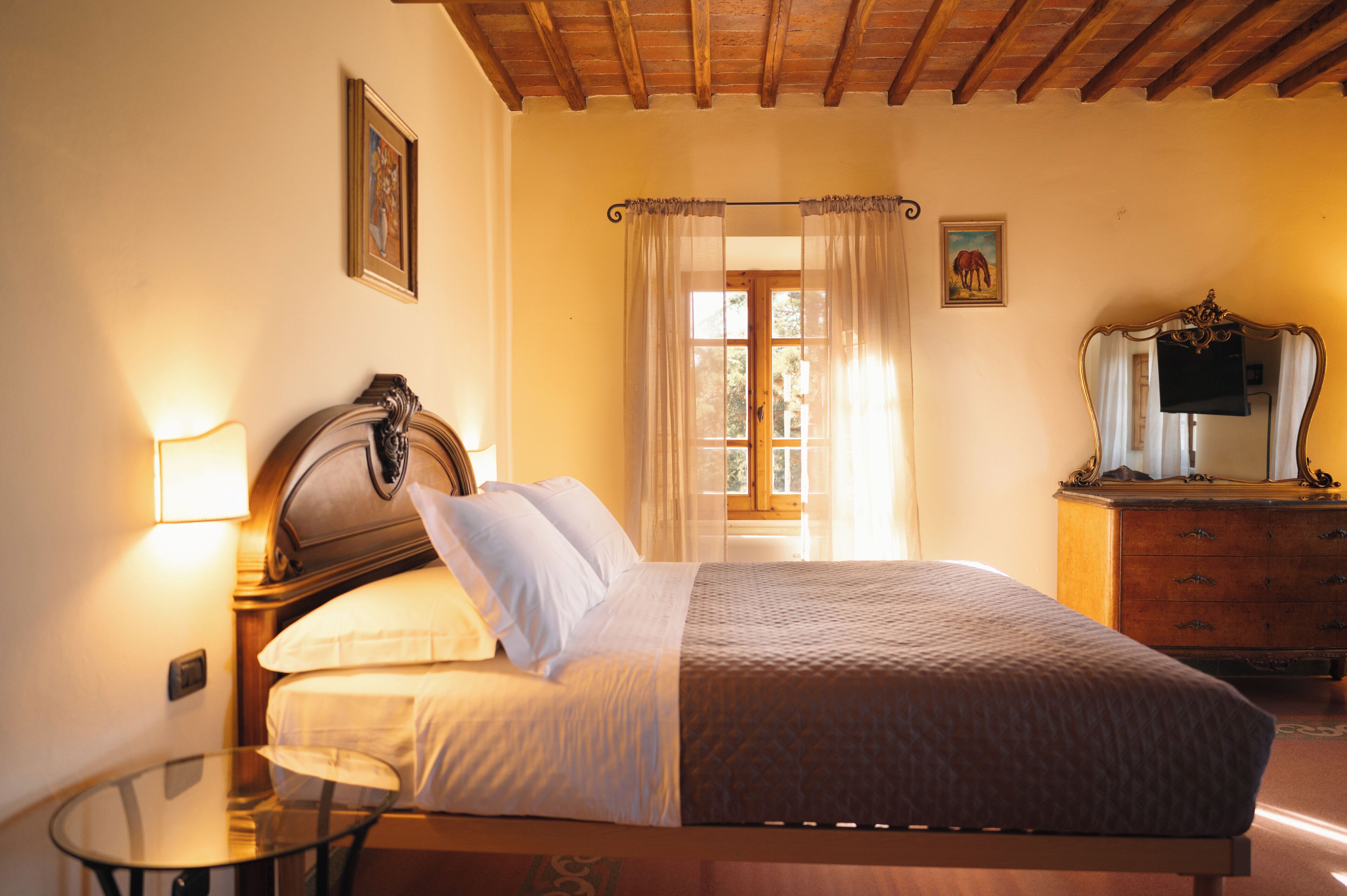 A bedroom with a wooden bed, a glass table, a dresser, and a window with curtains.