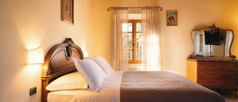 A bedroom with a wooden bed, a glass table, a dresser, and a window with curtains.