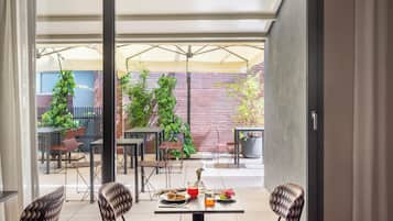 An outdoor patio with tables and chairs, a brick wall, and potted plants.