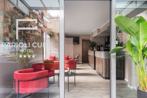 Een hotellobby met rode zitplaatsen, een receptiebalie en uitzicht op buiten.