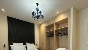 A modern bedroom with a large bed, a built-in wardrobe, and a chandelier. - Residence VillaBelleFleur-Apartment La Centaurée (Château-Ville-Vieille)
