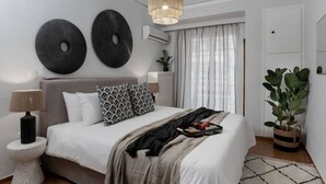 Ein modernes Schlafzimmer mit einem großen Bett, zwei Wanddekorationen in Kreisform, einer Pendelleuchte, einer Nachttischlampe, einem Topfpflanzen und einem Fenster mit durchsichtigen Vorhängen.