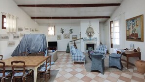 Amplia sala de estar con techo alto, chimenea y comedor con mesa y sillas.