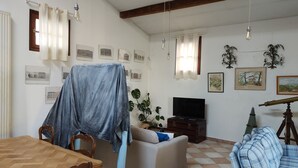 Una sala de estar con una mesa de comedor de madera, un sofá, un televisor y un telescopio.