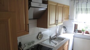 A kitchen with wooden cabinets, a stainless steel sink, and a coffee maker.