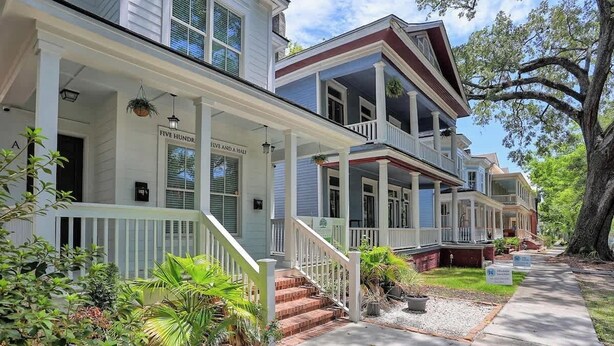 A two-story house with a porch, steps, and potted plants. - Fun & Renovated Artsy Downtown Apt Dog Friendly with Fully Fenced Backyard and Private Parking (Savannah)