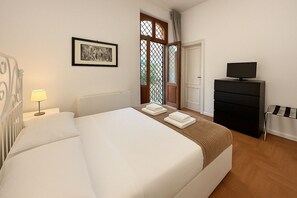 A hotel room with a large bed, a desk with a computer, a TV, and a window with a view. - Femi Castle (Roma)