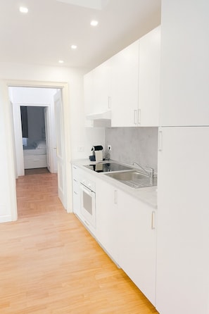 A modern kitchen with white cabinets, a stainless steel sink, and a built-in oven.