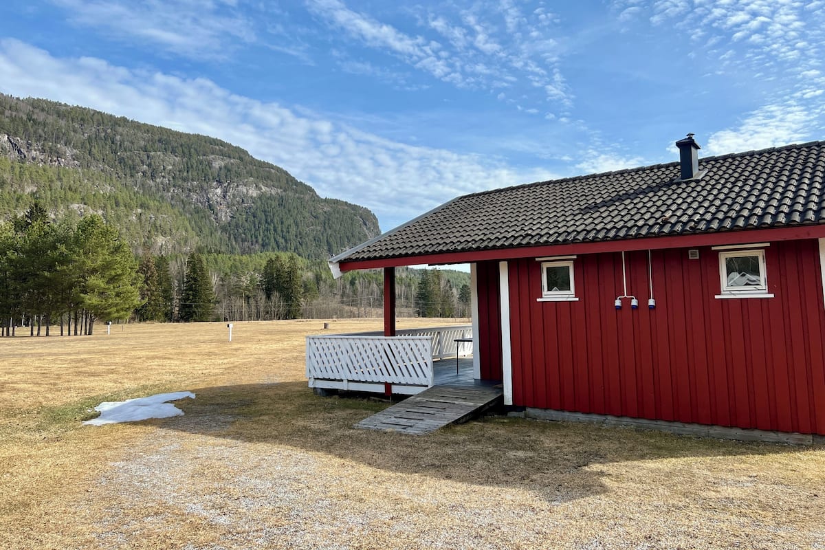 En röd byggnad med ett tak täckt av tegelpannor, en inglasad veranda och en grusuppfart.