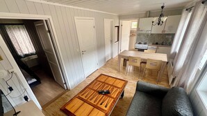 A compact living space with a sofa, a coffee table, a kitchen area with a stove and cabinets, and a door leading to another room. - Sanda Camping (Midt-Telemark)