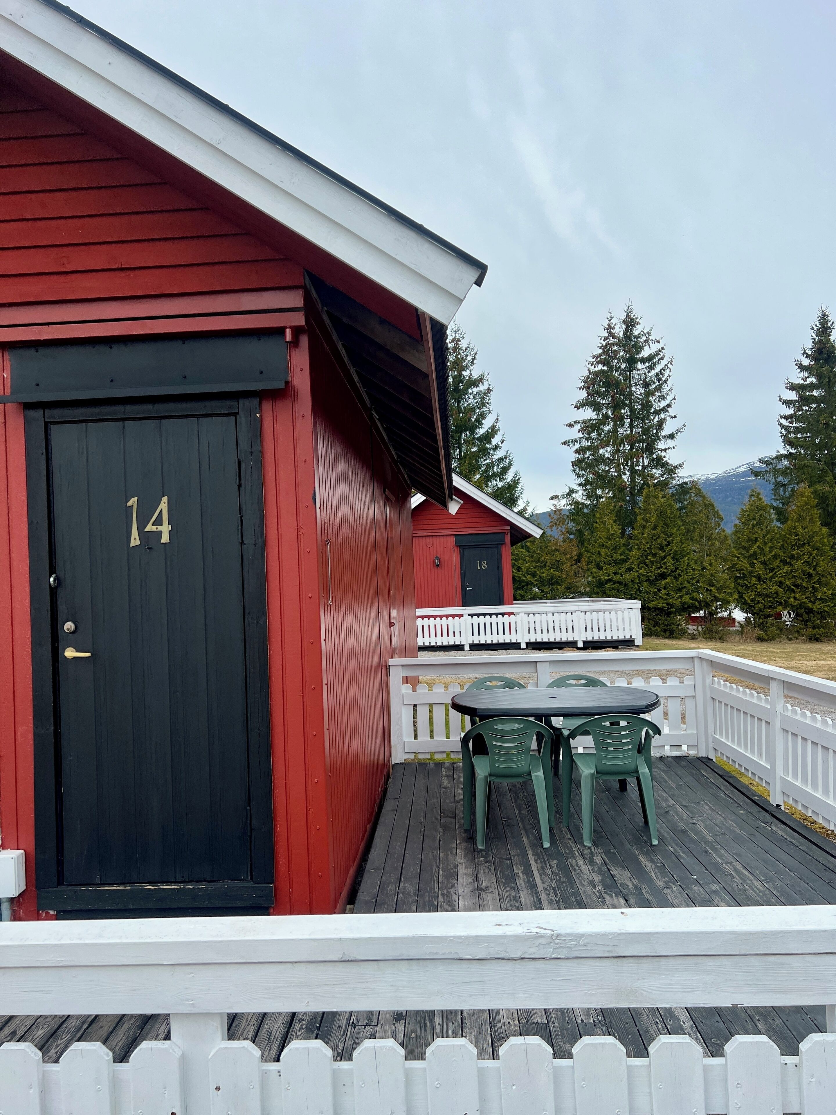 A red building with a black door marked "14" and a white picket fence.