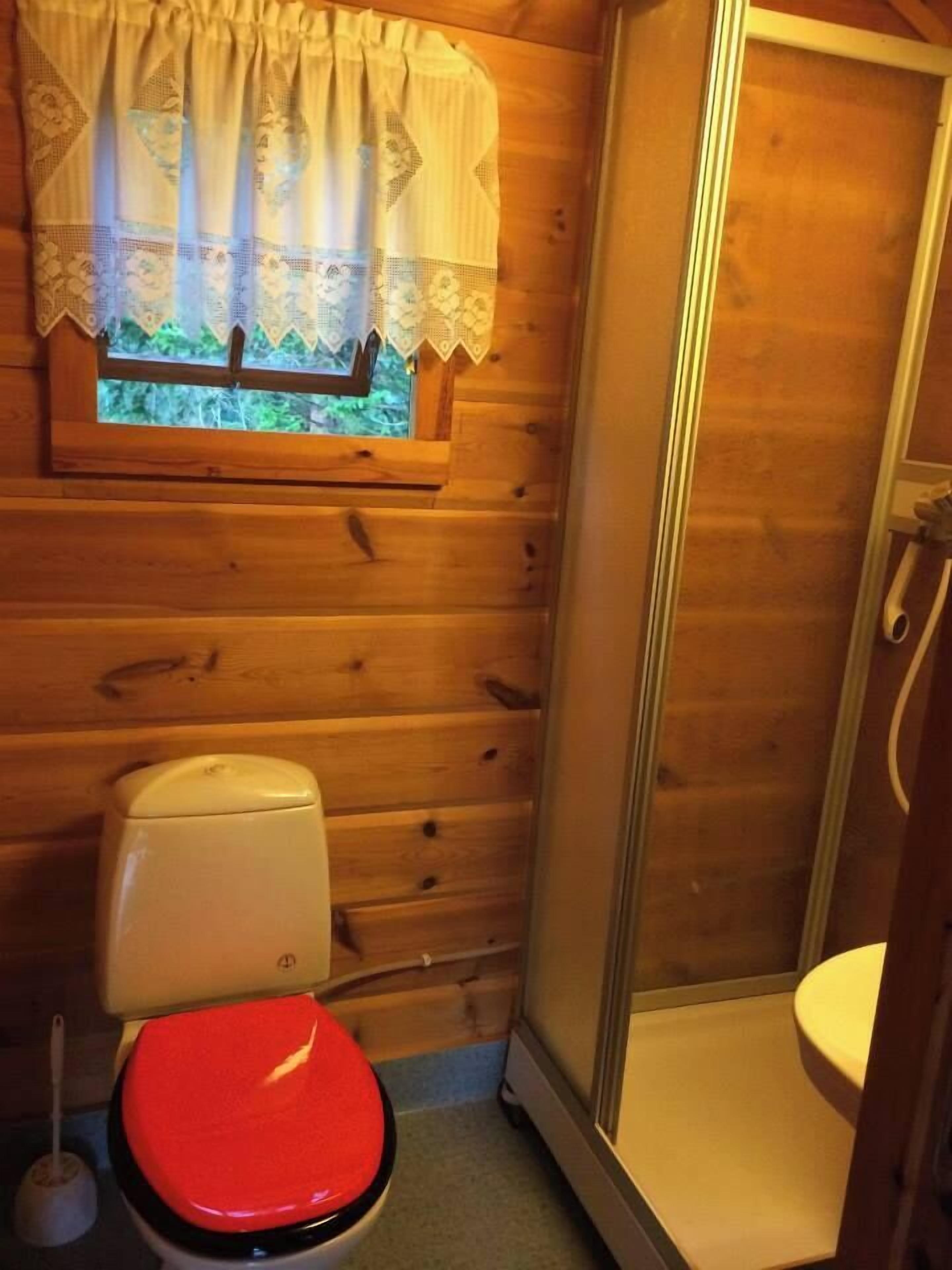Pieni kylpyhuone, jossa on wc, suihku ja ikkuna, jossa on verho.