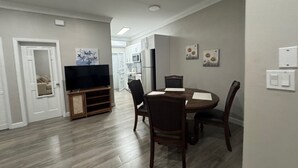 Un comedor con una mesa redonda, sillas, un televisor y obras de arte en las paredes.