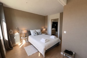 A bedroom with a bed, bedside lamps, a radiator, a mirror, and a small table with a device. - Chez Malé -Apartment with terrace and car park, Jourdan parc, Aix- Chez Malé (Aix-en-Provence)