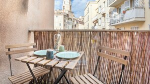 Ein Balkon mit Bambuszaun, Holzstühlen und einem Tisch, gedeckt mit Tellern und einer Vase.