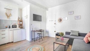 Eine moderne Wohnung mit Küche, Essbereich und Wohnzimmer. Sie verfügt über einen Flachbildfernseher, ein Sofa und einen Couchtisch.