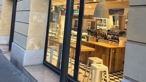 Una tienda Monoprix con un amplio ventanal de vidrio, un mostrador de madera y un suelo con estampado de cuadros.