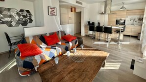 Una sala de estar moderna con un sofá, una mesa de centro y una cocina al fondo.