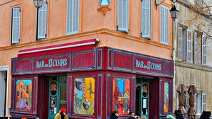 A colorful bar with outdoor seating, murals, and a statue. - Le Panier- Superb duplex with sea view, terrace and spa bath (Marseille)
