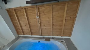 A bathroom with a bathtub, wooden paneling above, and a shower area. - Le Panier- Superb duplex with sea view, terrace and spa bath (Marseille)