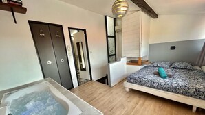 A bedroom with a bed, a large window, a wooden floor, and a bathtub. - Le Panier- Superb duplex with sea view, terrace and spa bath (Marseille)