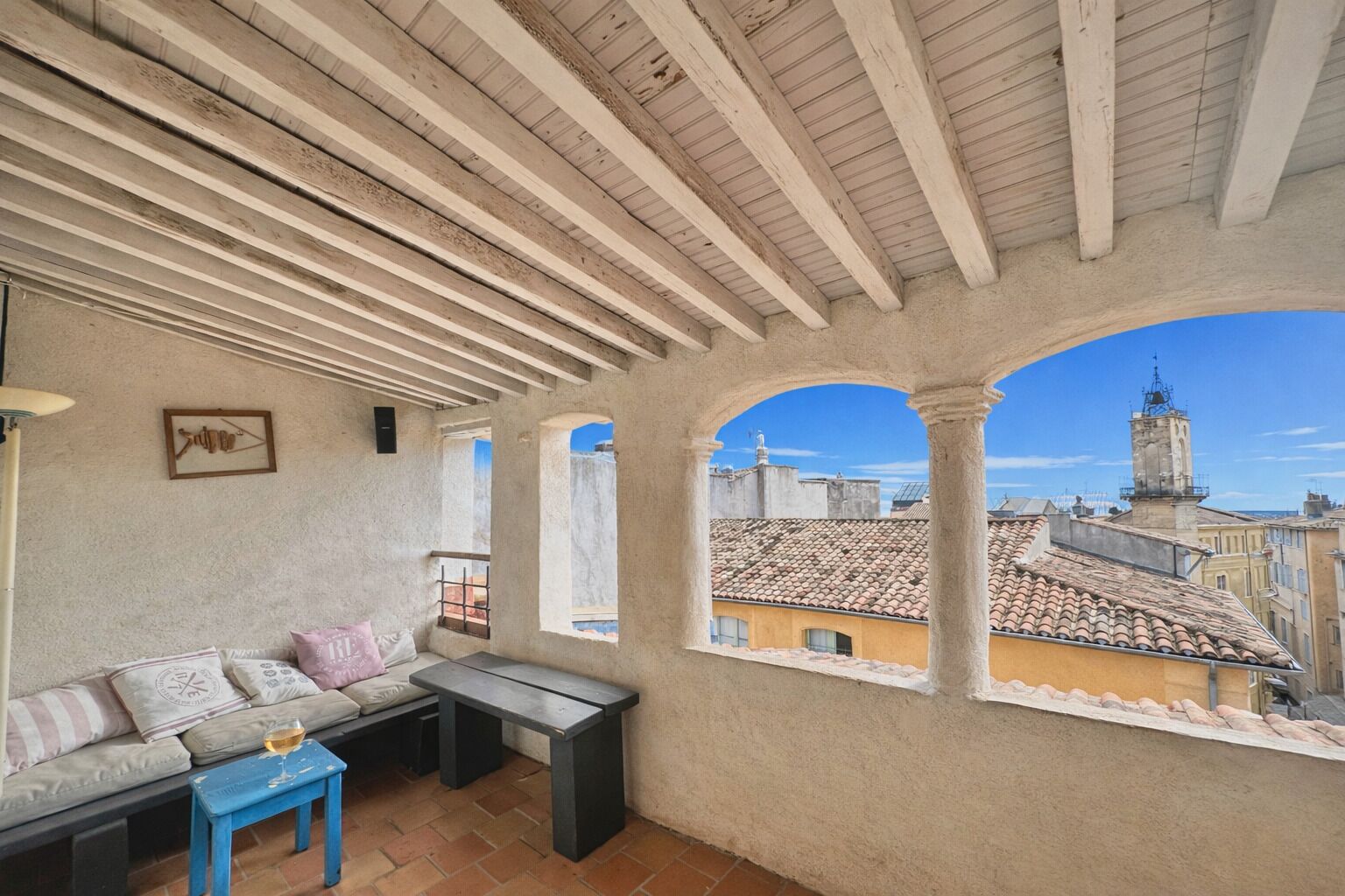 Ein Balkon mit einer Couch, einem kleinen Tisch und einem Weinglas.