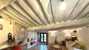 A spacious living area with exposed wooden beams, a white brick wall, a white sofa, red bar stools, and a coffee machine. - Toit Vieil - Terrace with stunning view over Aix rooftops (Aix-en-Provence)