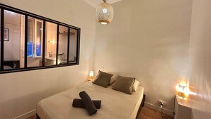 Ein Schlafzimmer mit einem großen Bett, einem Spiegel, Nachttischlampen und einer Deckenleuchte.