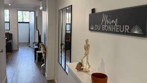 A hallway with a white wall, a wooden mannequin, a potted plant, and a sign that reads "Maison DU BONHEUR". - L'Amandier - Lovely New 2-Bedroom apt in Aix City Center (Aix-en-Provence)