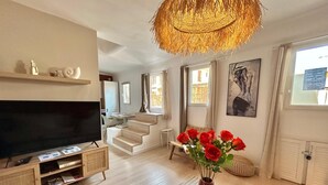 A modern living room with a flat-screen TV, a staircase, a dining area, and a large window. - La Petite Lucarne - Vieux Port, Center Marseille/Panier (Marseille)