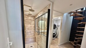 A modern bathroom with a glass shower enclosure, a built-in washing machine, and a wooden staircase. - La Petite Lucarne - Vieux Port, Center Marseille/Panier (Marseille)