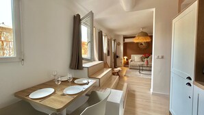 A modern dining area with a wooden table set for four, a sofa, and a hanging light fixture. - La Petite Lucarne - Vieux Port, Center Marseille/Panier (Marseille)