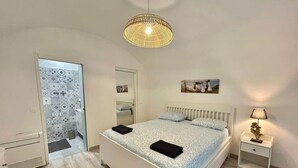 Ein Schlafzimmer mit Bett, Nachttisch, Lampe und Pendelleuchte.