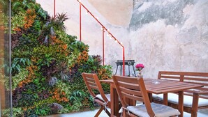 Ein Holztisch mit Stühlen vor einer Wand mit vertikalem Garten.