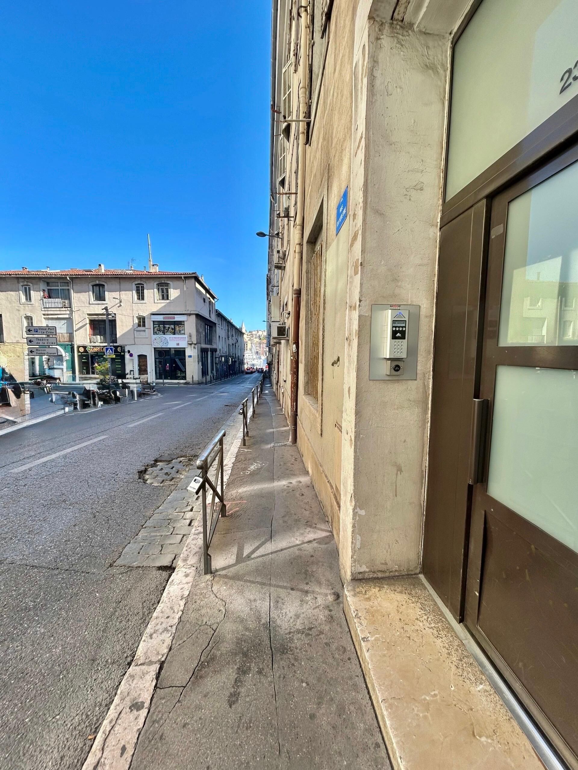 Une vue de rue montrant un immeuble doté d’une grande porte vitrée et d’un clavier de sécurité.