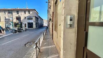Une vue de rue montrant un immeuble doté d’une grande porte vitrée et d’un clavier de sécurité.