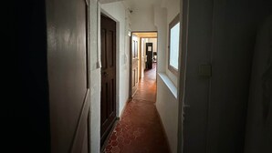 A narrow hallway with a tiled floor leading to a room with a window. - Chez Florence - Spacious 1BR in Historic City Center (Aix-en-Provence)
