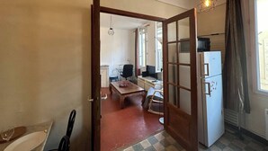 A compact living space with a kitchenette, a dining area, and a bedroom. - Chez Monique - 1BR in historic city center, mairie square (Aix-en-Provence)