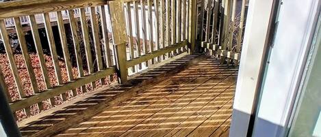 Un ponteggio in legno con ringhiera, un albero e una casa sullo sfondo.